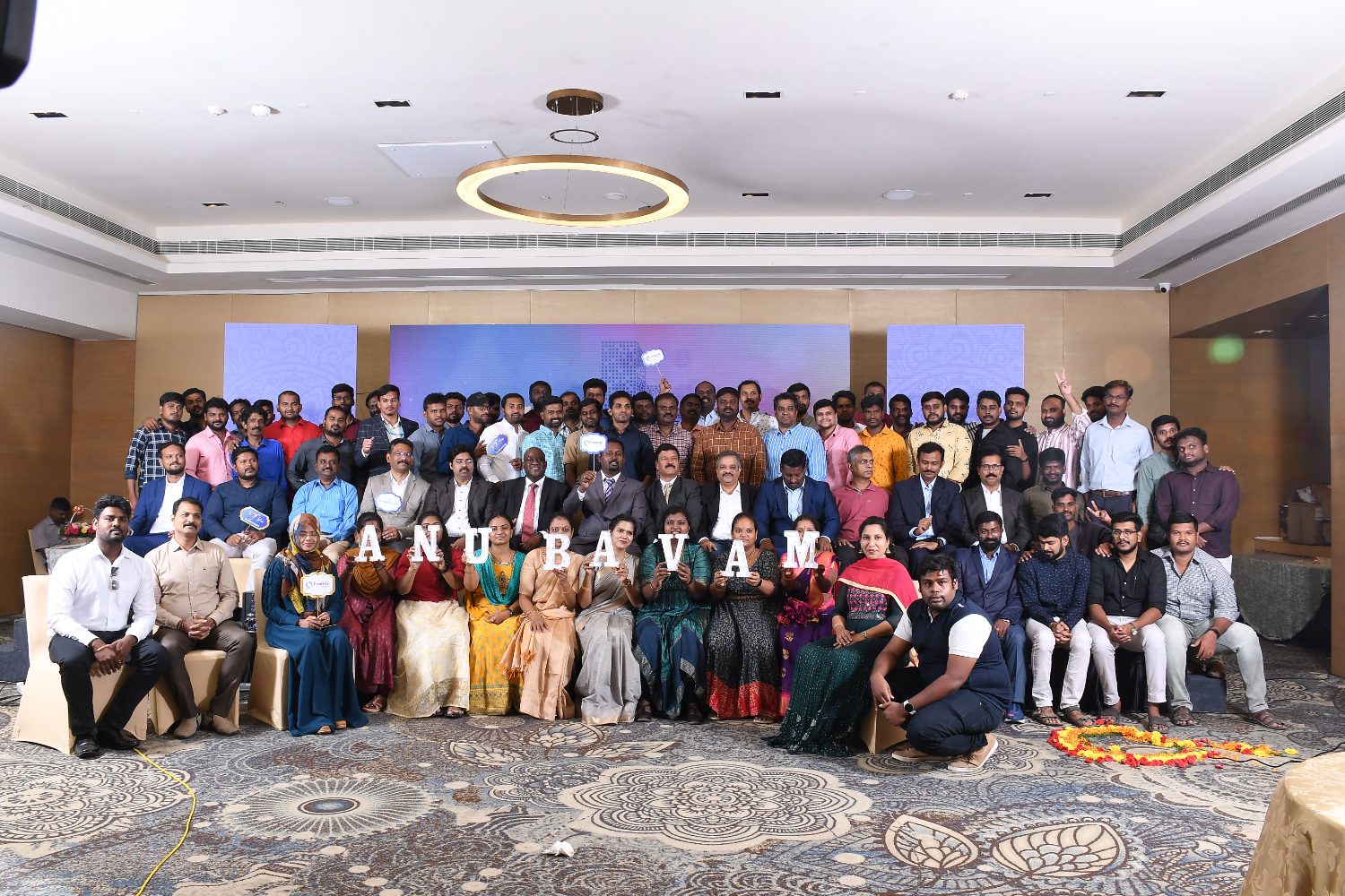 The whole company holding letters spelling Anubavam at the annual day