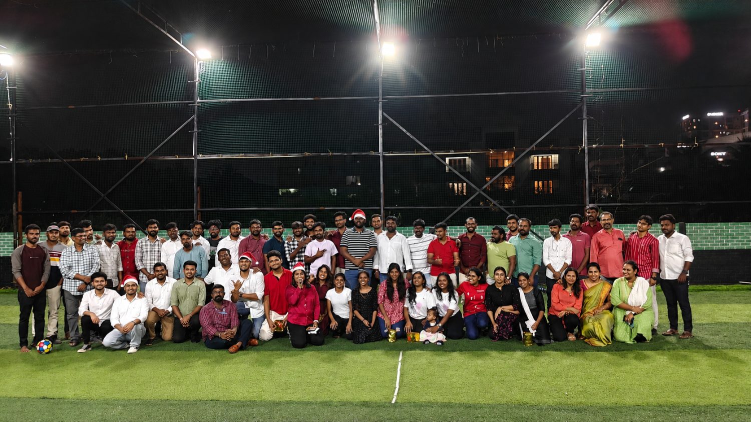 The team at a year-end get-together on a floodlit turf ground